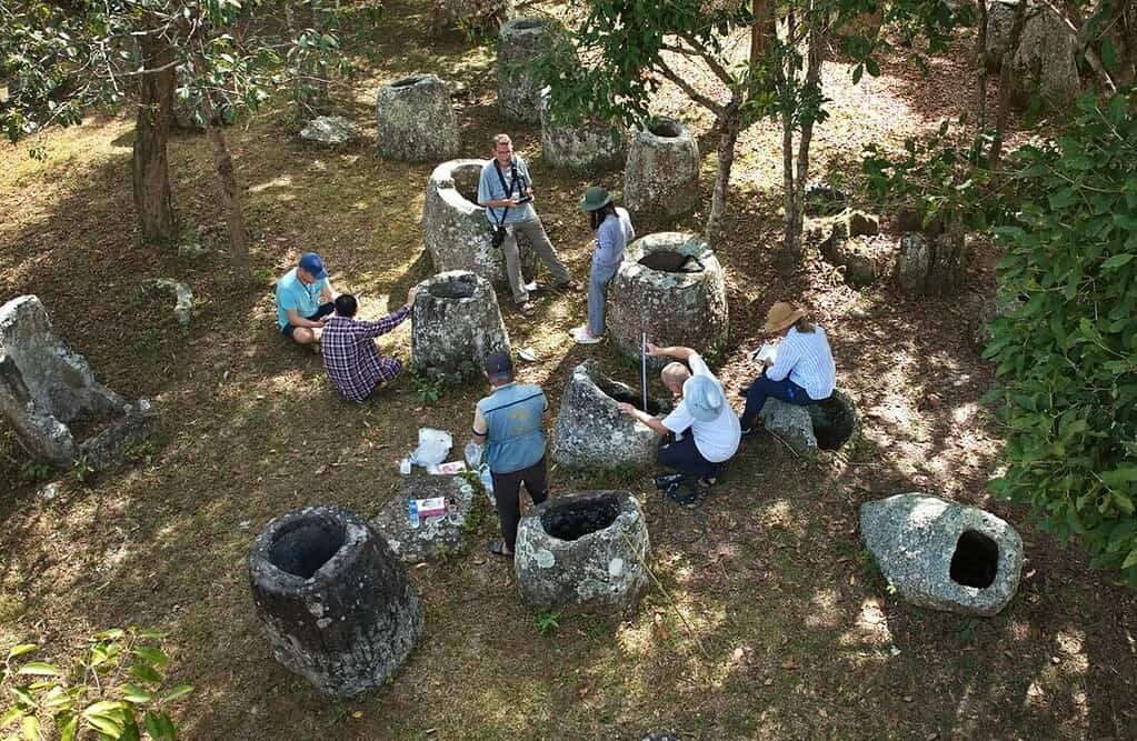 Ancient Burial Jars in Laos Have Been Running a 2,000-Year Natural Experiment 3 Researchers gathered taking measurements around many ancient stone burial jars in a forest
