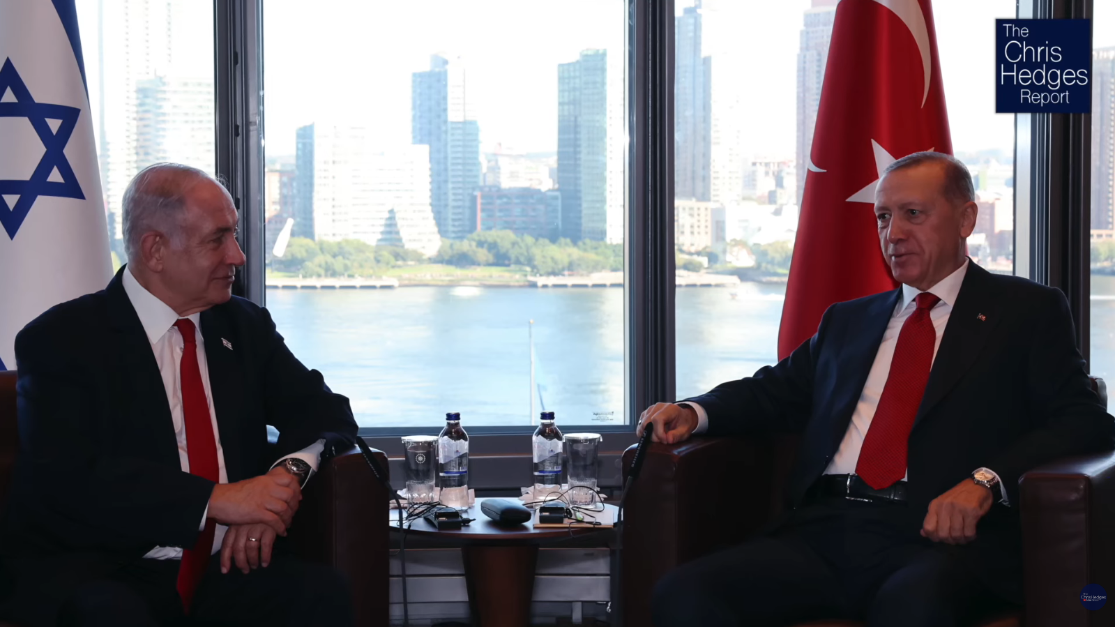 Israeli Prime Minister Benjamin Netanyahu seated on the left facing Turkish President Recep Tayyip Erdoğan on the right in armchairs during a diplomatic meeting in front of a high-rise window overlooking a river.