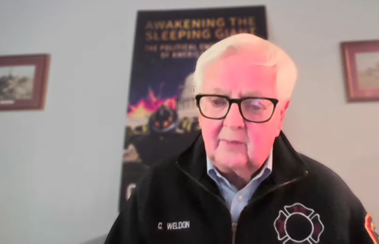 Former Congressman Kurt Weldon speaking during a video interview wearing a black embroidered firefighter jacket.