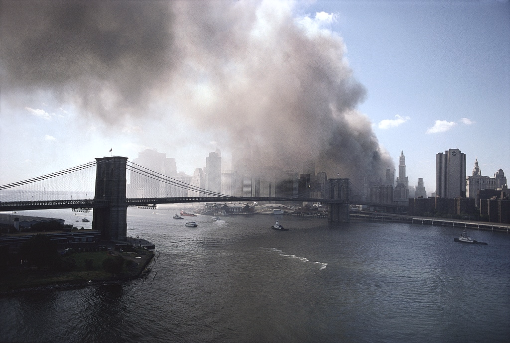 Thick plumes of smoke rising over Lower Manhattan behind the Brooklyn Bridge following the World Trade Center collapse on September 11, 2001.