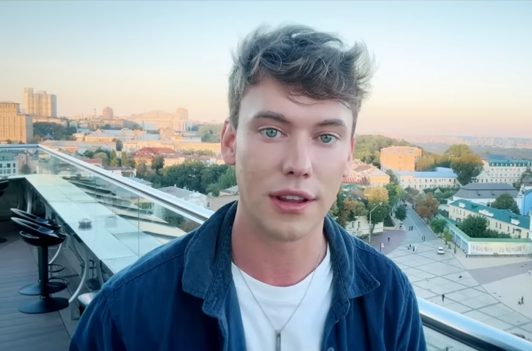 Selfie portrait of British YouTuber Caolan Robertson outdoors with city architecture and a bridge in the background in Kyiv, Ukraine.