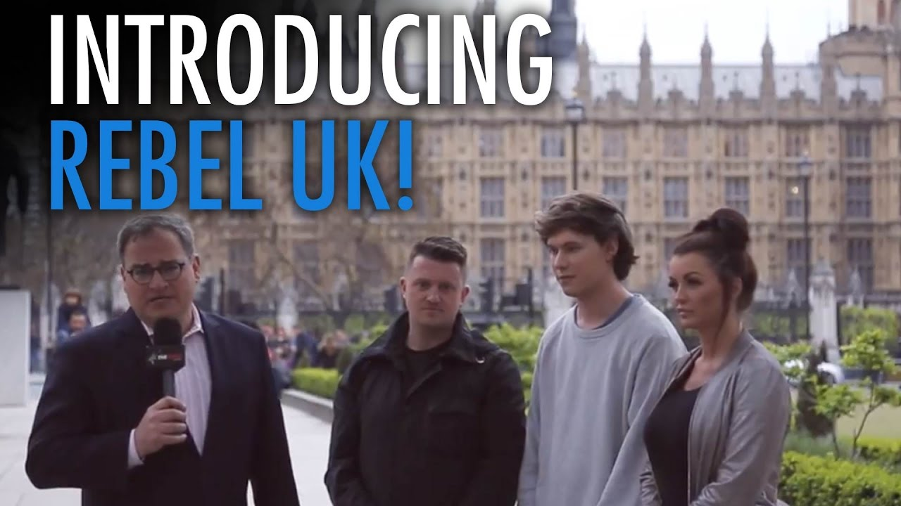 Ezra Levant speaking into a microphone alongside Tommy Robinson, Caolan Robertson, and Faith Goldy in front of the UK Parliament for the launch of Rebel UK.