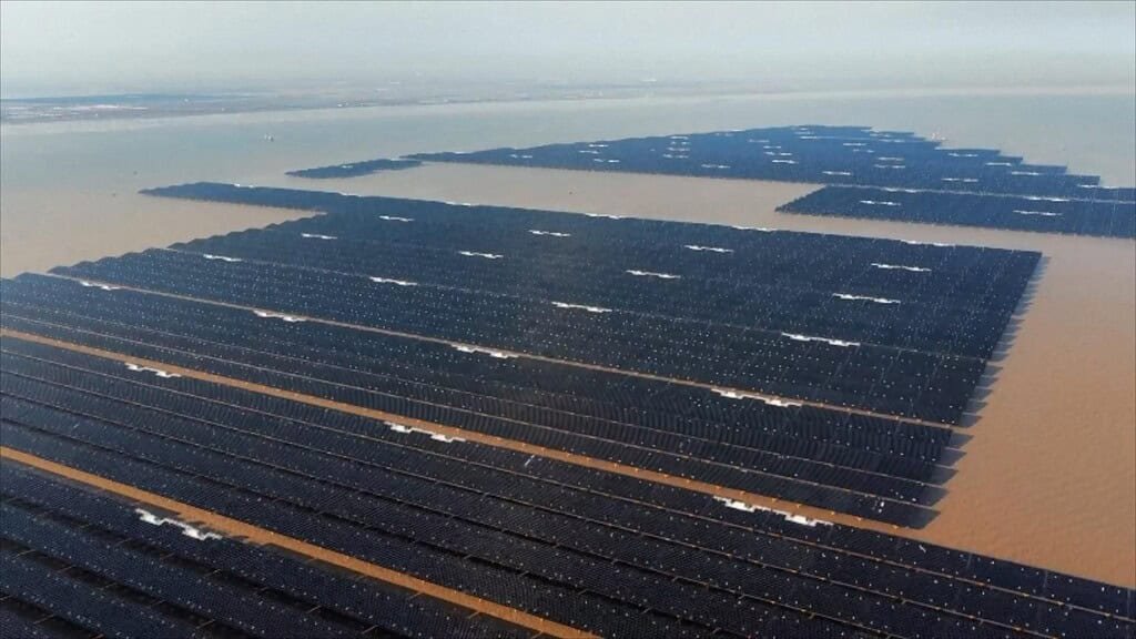 Offshore floating solar plant. many solar panels atop a largely brown body of water.